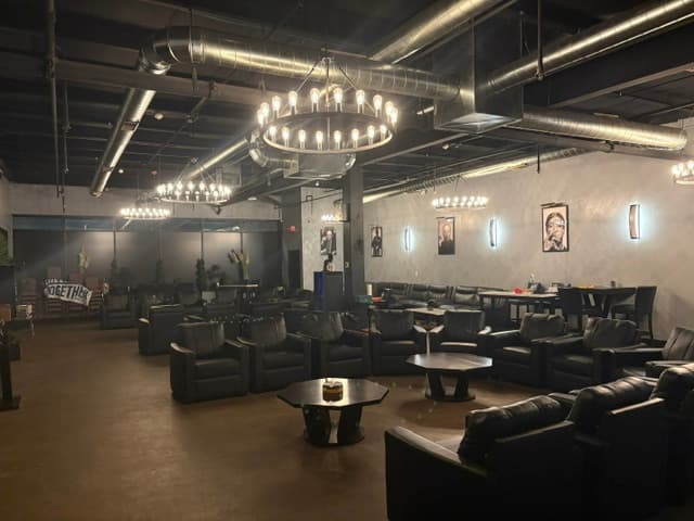 Wide lounge view with iron chandelier, portraits, and leather seating