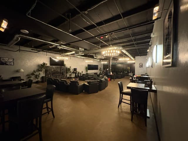 Full venue panorama with TVs, high-top tables, leather seating, and chandeliers